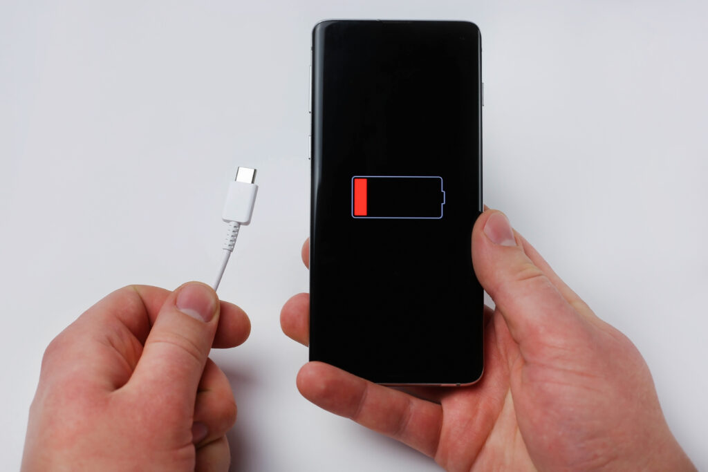 holds charging cable smartphone showing low battery holds charging cable smartphone showing low battery