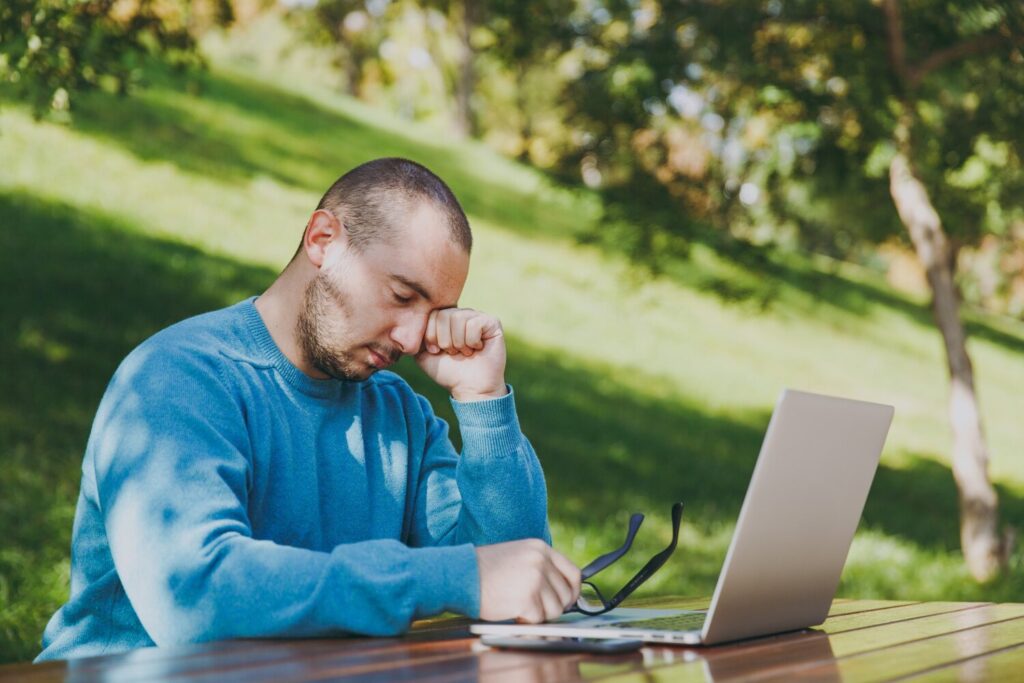 young tired sad man businessman student casual blue shirt glasses sitting table with mobile phone city park using laptop working outdoors worries about problems mobile office concept 365776 8690 young tired sad man businessman student casual blue shirt glasses sitting table with mobile phone city park using laptop working outdoors worries about problems mobile office concept 365776 8690